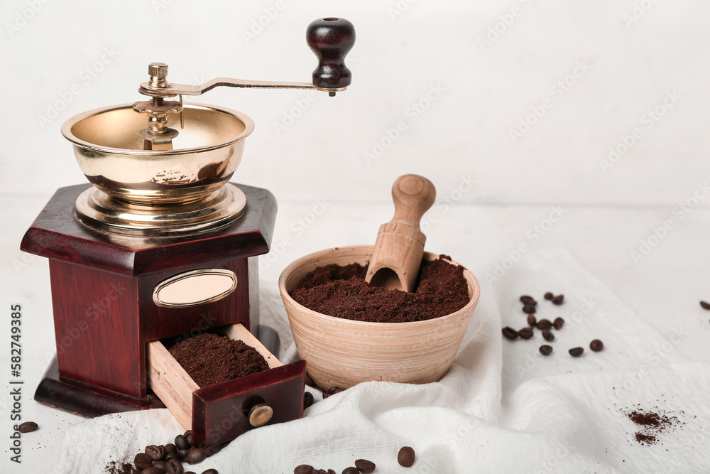 Bowl of coffee powder with scoop and grinder on white table