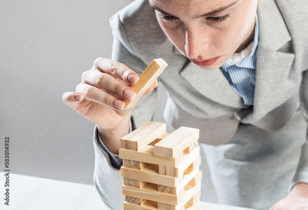 Business woman building tower from wooden blocks