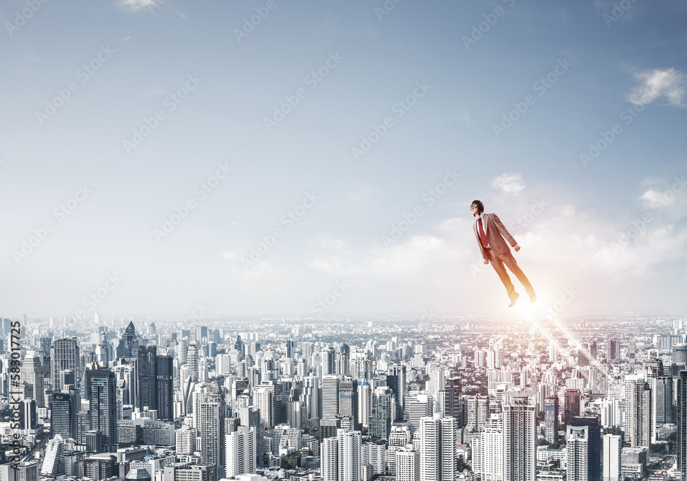 Businessman in suit and aviator hat flying in sky