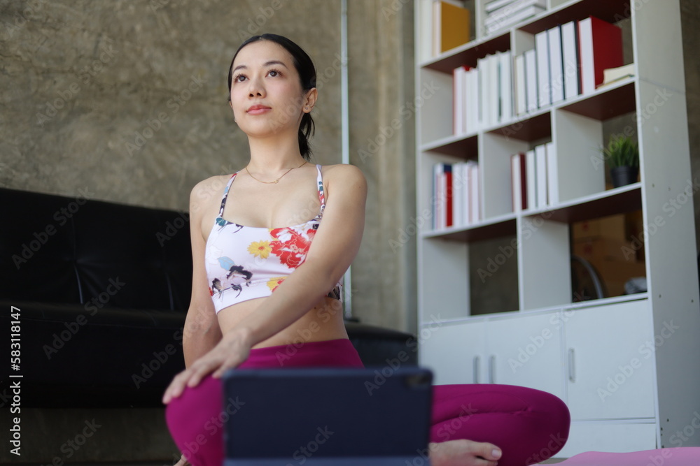 Beautiful asian woman doing relaxing exercise at home and practicing yoga in quiet living room.