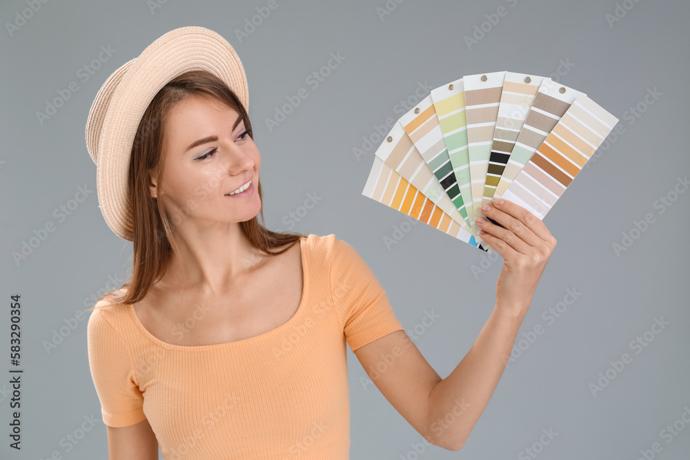 Beautiful woman with paint color palettes on grey background