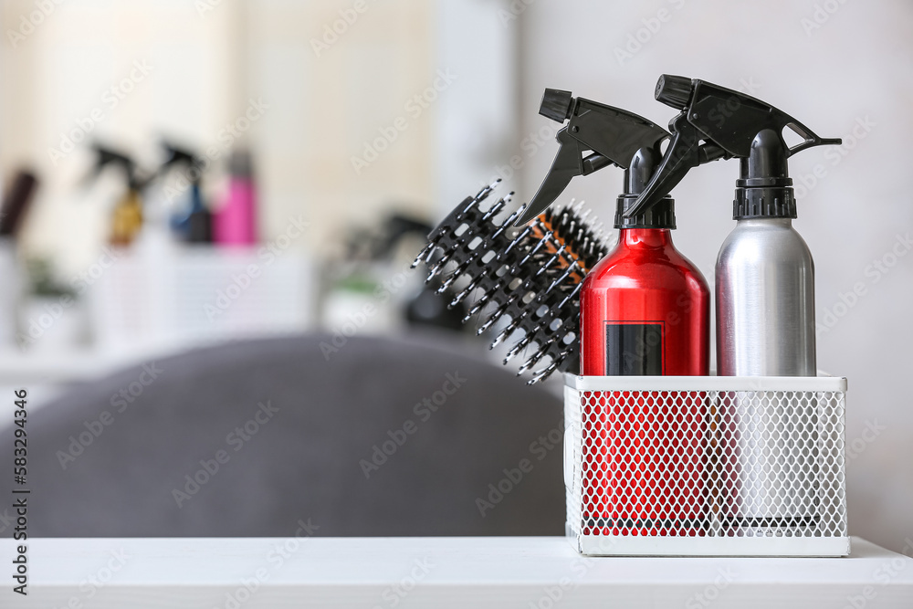 Organizer with hair sprays and brushes on table in beauty salon, closeup