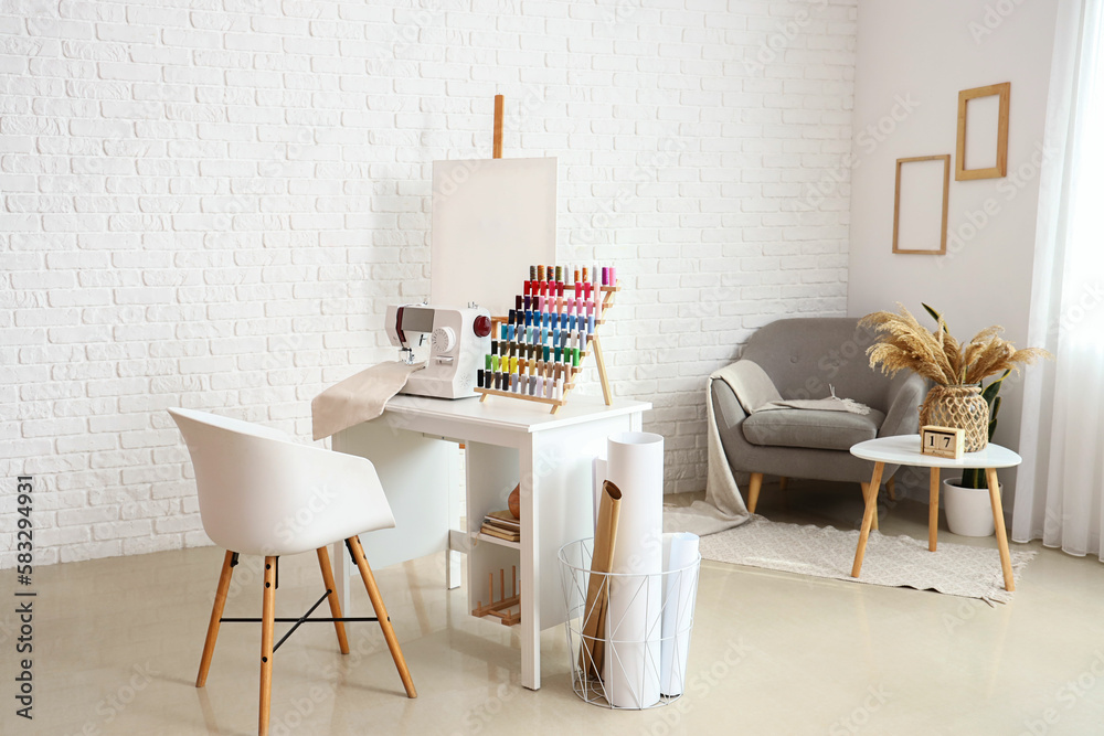 Interior of atelier with tailors workplace, thread spools and easel