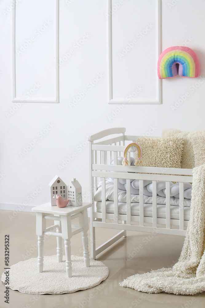 Interior of light childrens bedroom with baby crib and table