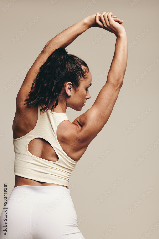 Rearview of an athletic woman stretching her arms in a muscle-toning exercise