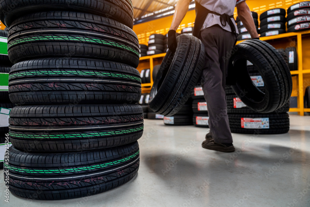 A male auto mechanic storing or stocking new tires at a large warehouse at a service center or auto 