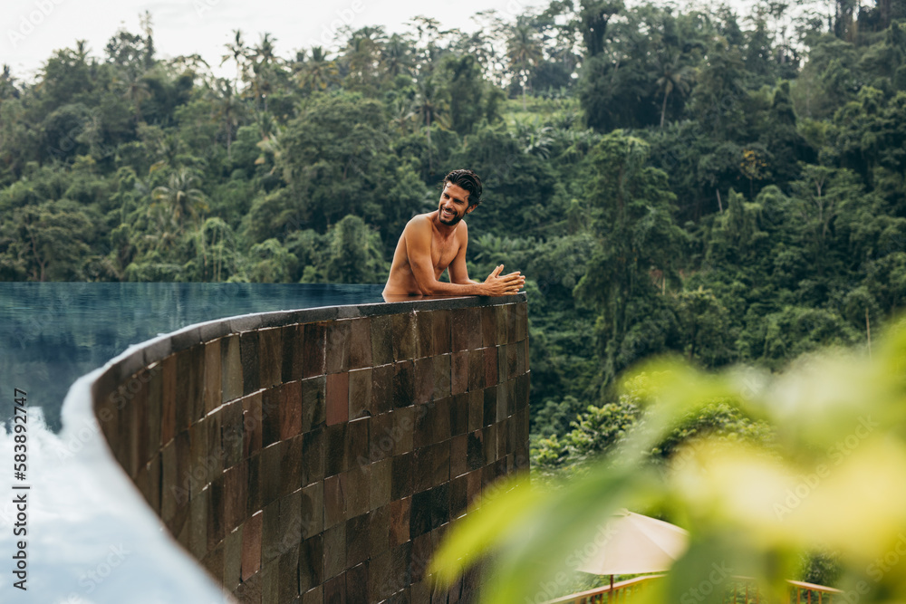 Handsome young man relaxing in pool at holiday resort