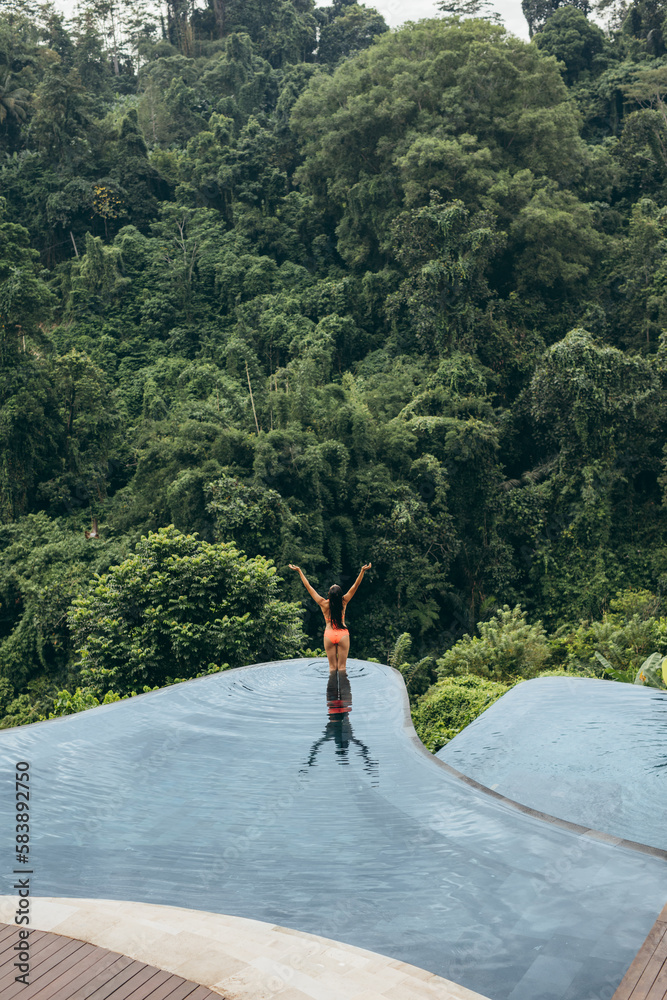 Woman with hands raised standing in swimming pool