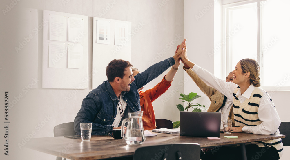 Successful business people high fiving each other during a meeting