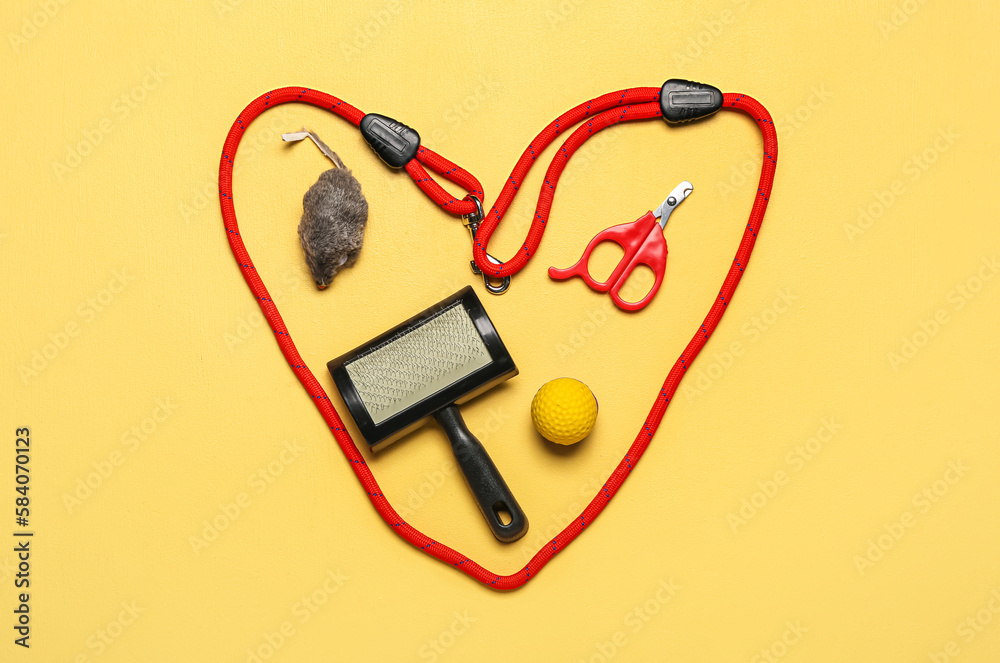 Heart made of pet care accessories on yellow background