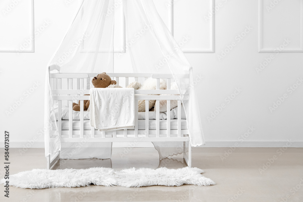 Baby crib with toy bear in light bedroom