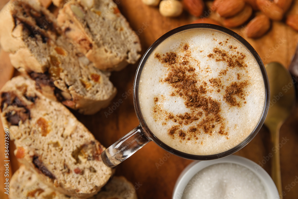 Board with delicious biscotti cookies, nuts and cup of coffee on wooden background