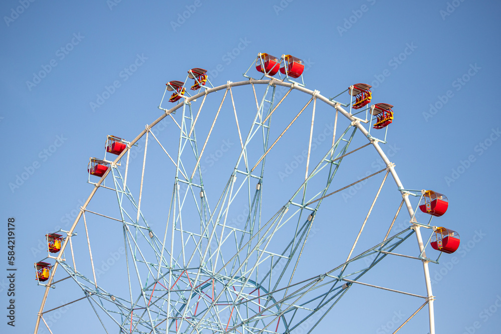 Ferris wheel, booths against the blue sky.