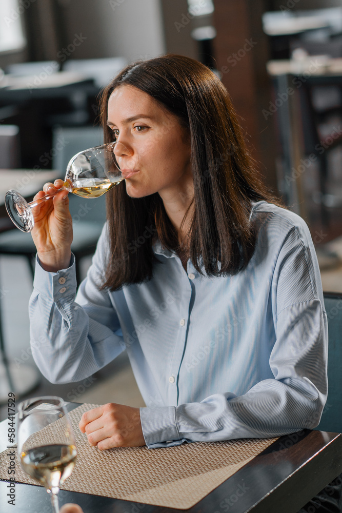 A date in a hotel restaurant a woman drinks white wine from a glass close-up