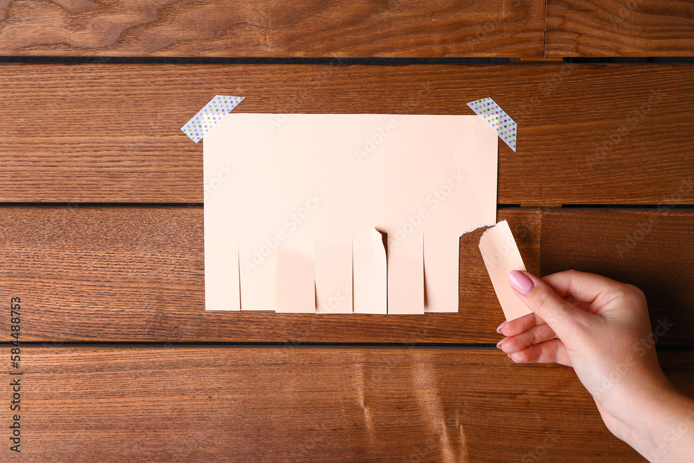 Woman tearing off paper ad on wooden background