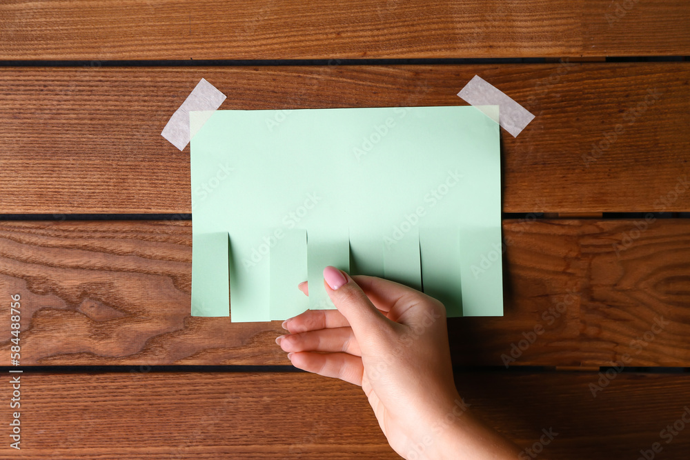 Woman tearing off paper ad on wooden background