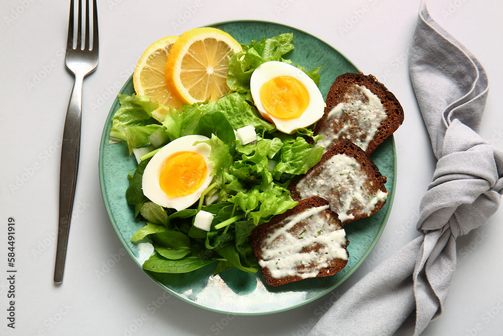 Plate of delicious salad with boiled eggs and cream cheese sandwiches on grey background