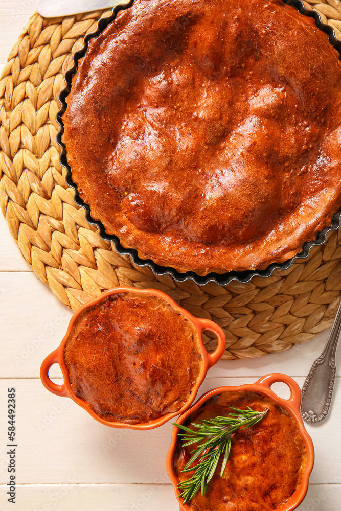 Delicious meat pies in baking forms on white wooden table