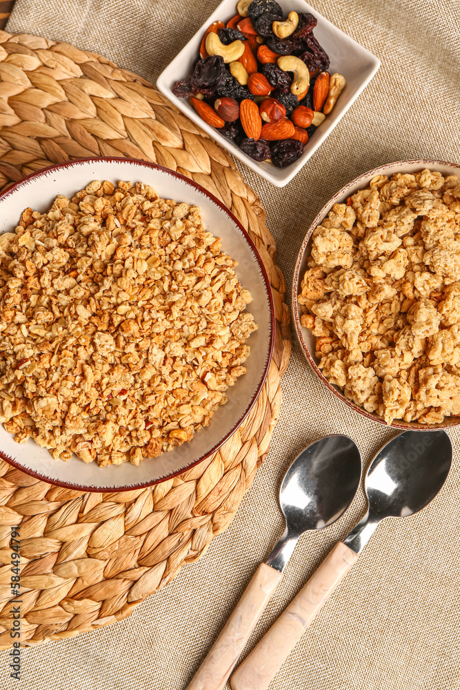 Bowls of tasty granola and nuts on table background