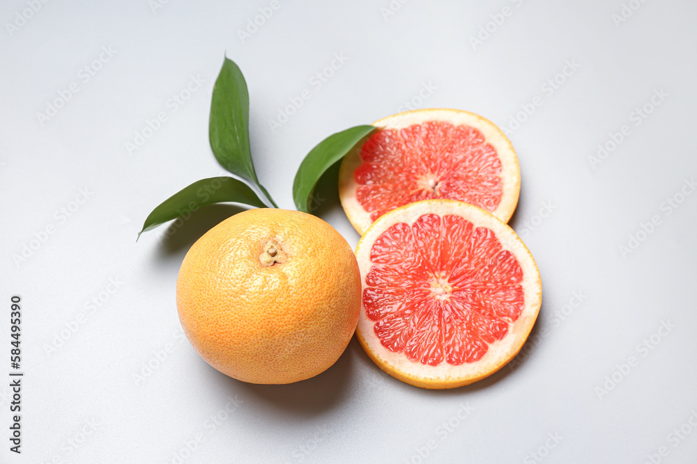 Ripe grapefruits and plant branch on light background