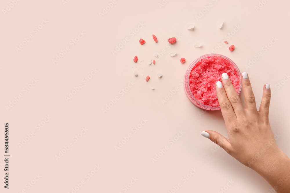 Female hand with jar of body scrub and sea salt on color background