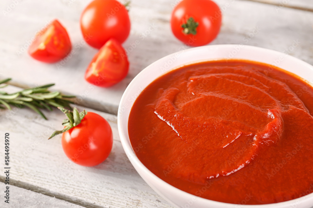 Bowl of tasty tomato paste on wooden background