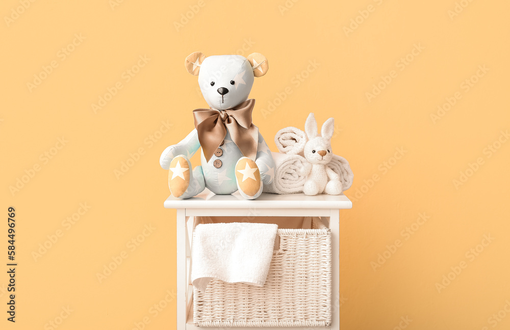 Toy bear and bunny with towels on shelf near beige wall