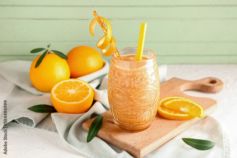 Glass of healthy orange smoothie and fresh fruits on table