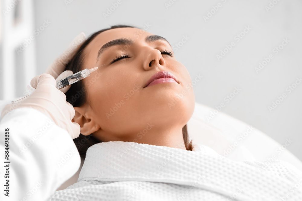 Young woman receiving filler injection in beauty  salon