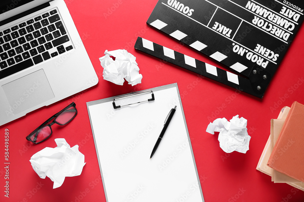 Clipboard with crumpled paper, laptop and movie clapper on red background