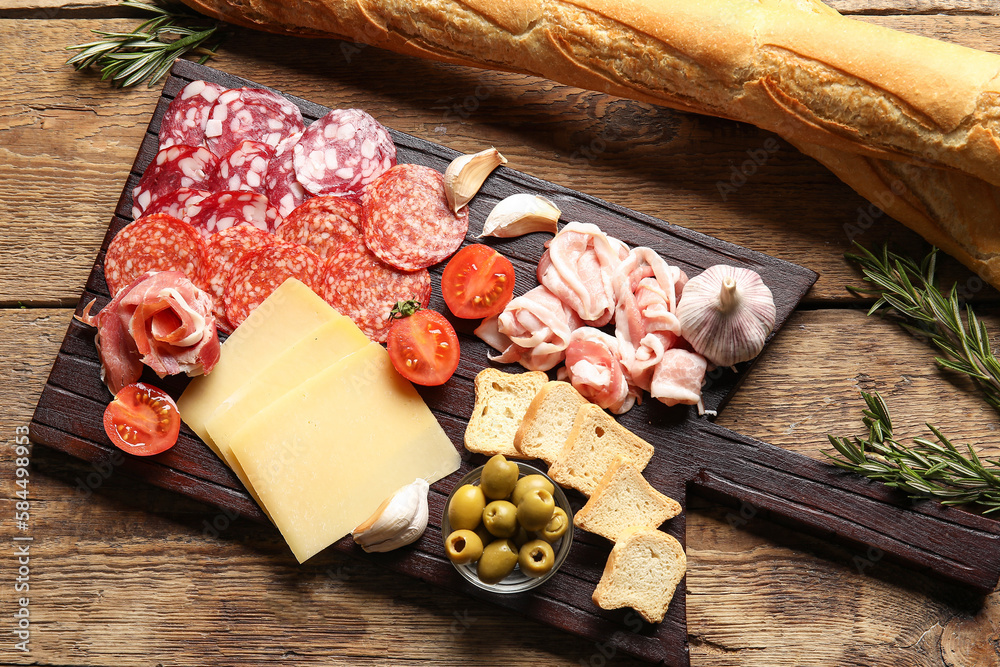 Board with assortment of tasty deli meats and cheese on wooden background