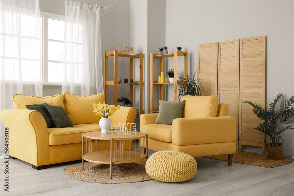 Interior of stylish living room with cozy sofa, armchair and flower vase on coffee table