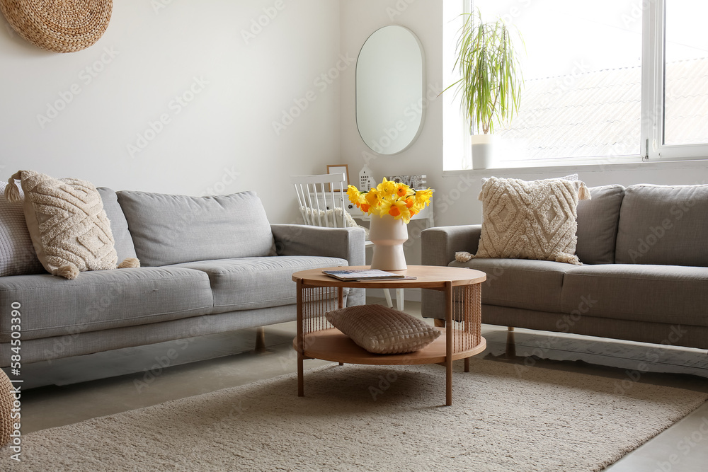 Interior of modern living room with cozy sofas and flower vase on coffee table