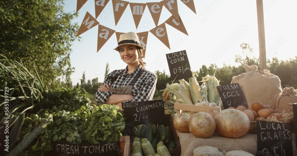 Portrait of young beautiful caucasian female farmer selling fresh groceries at farmers market stall.