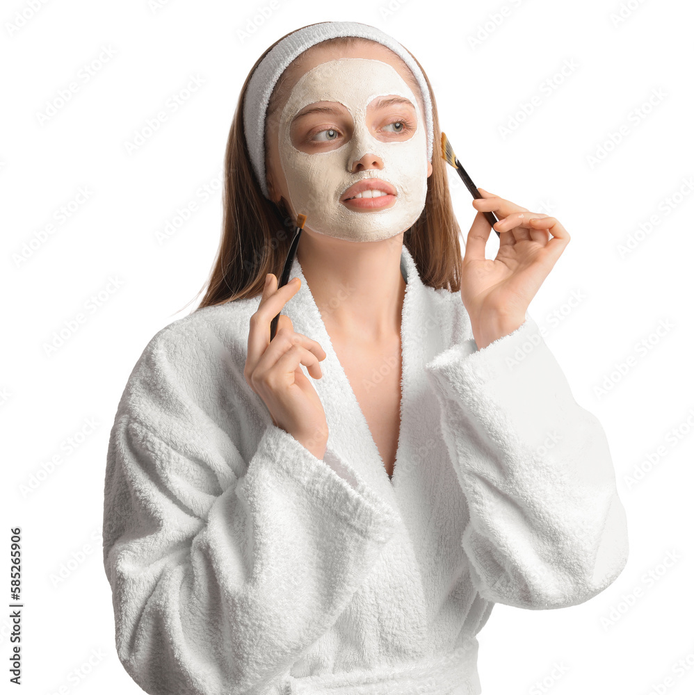 Young woman with applied turmeric mask and brushes on white background