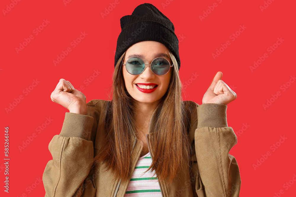 Happy young woman in sunglasses on red background, closeup