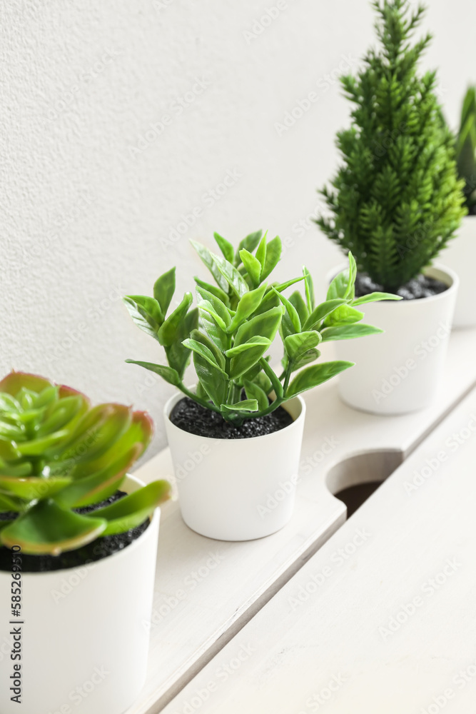 Artificial plants on table near light wall