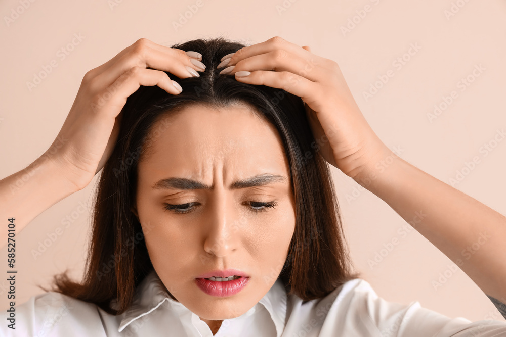 Worried young woman with hair loss problem on beige background