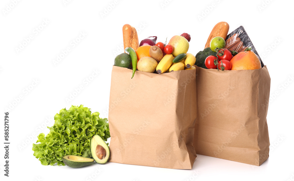 Paper bags with vegetables, fruits and sausages on white background