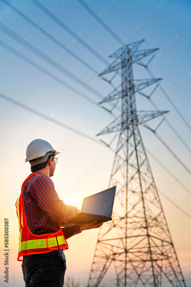 Asian electrical engineers checking location using a notebook computer standing at a power station t