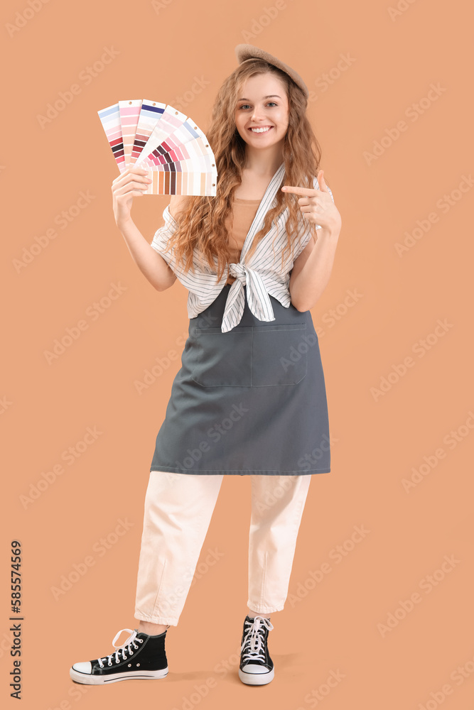 Female artist pointing at paint color palettes on beige background