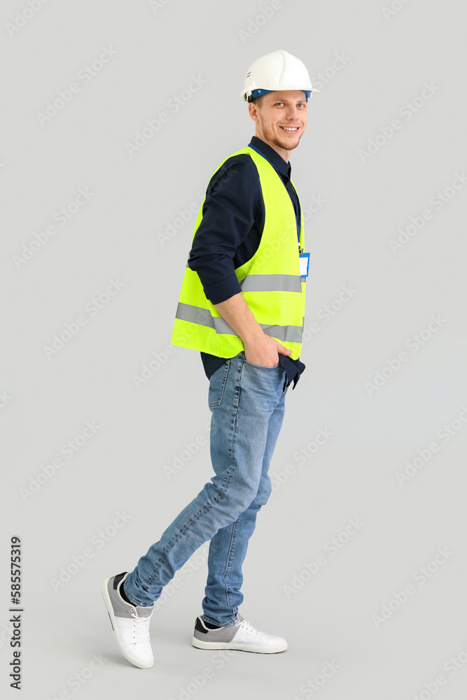 Male worker in vest and hardhat on grey background