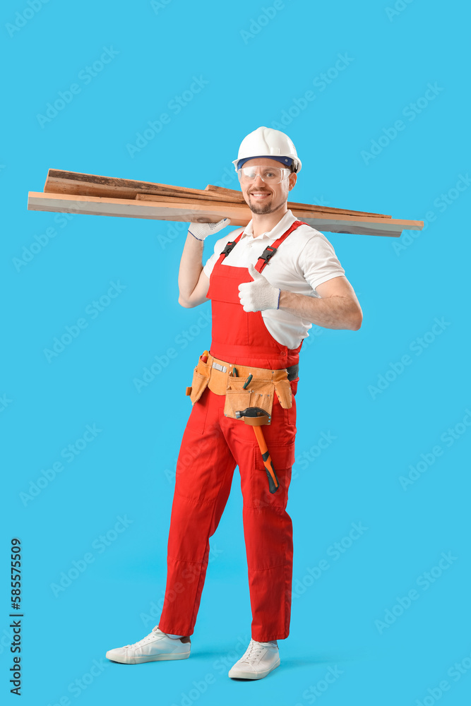 Male carpenter with wooden planks showing thumb-up on blue background