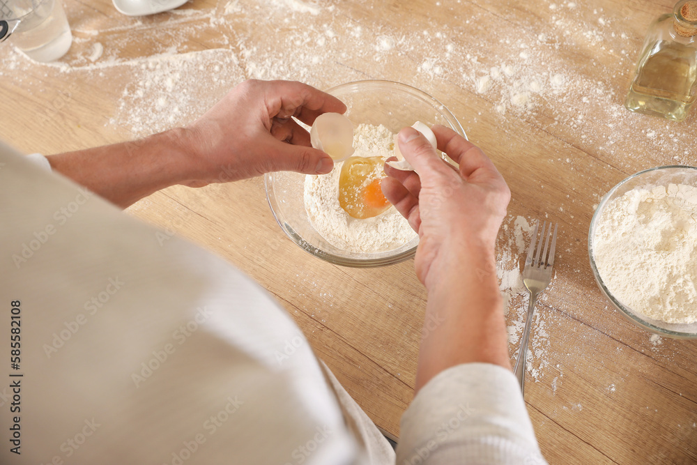 Male chef making dough for pasta at table in kitchen, closeup