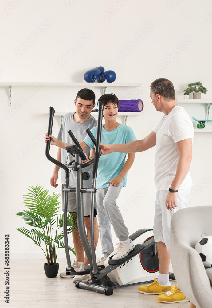 Happy little boy with his dad and grandfather exercising at home