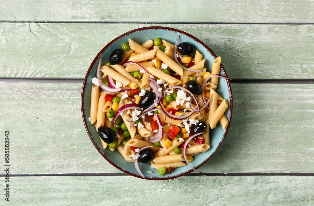 Bowl with tasty pasta salad on light wooden background