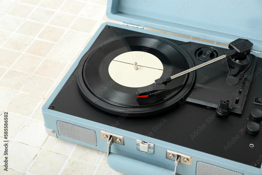 Record player with vinyl disk on beige tile table, closeup