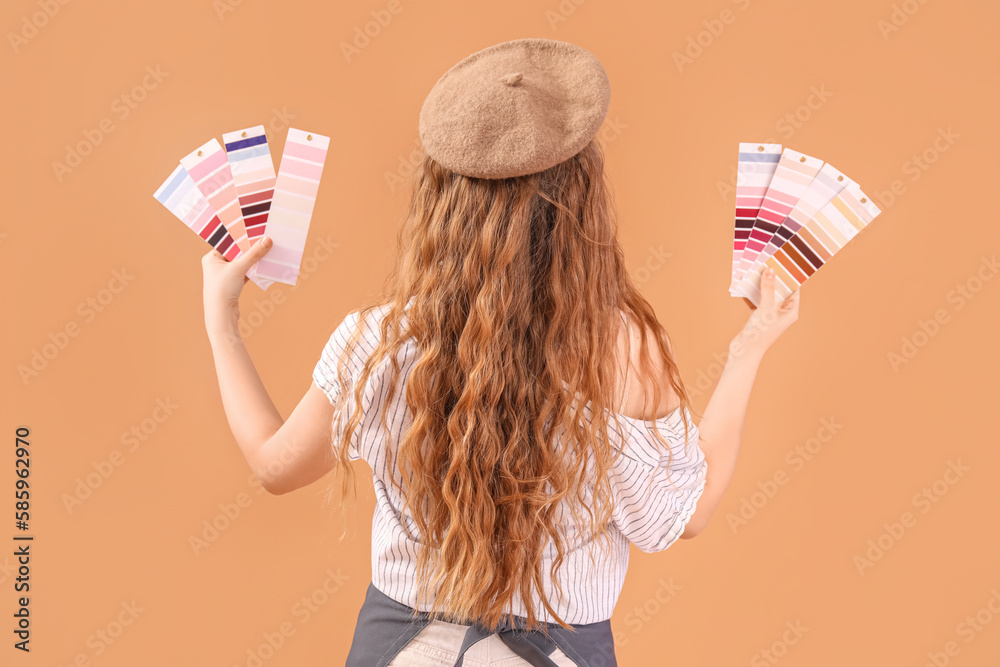 Female artist with paint color palettes on beige background, back view