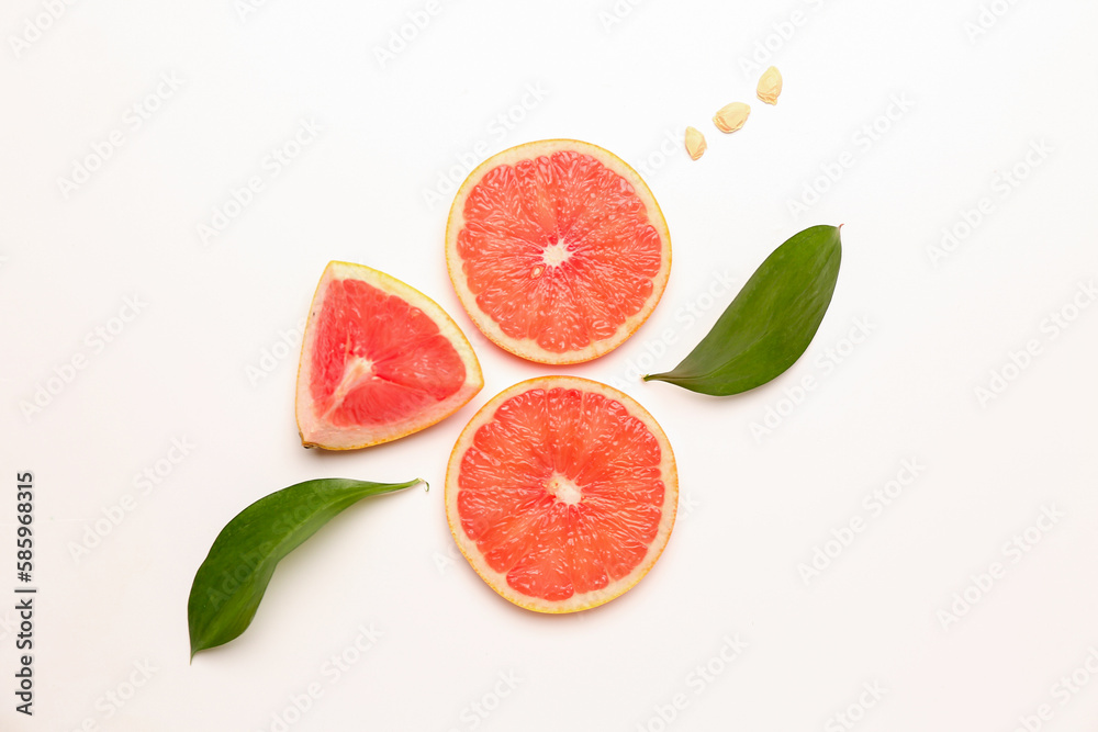 Composition with pieces of ripe grapefruit, seeds and plant leaves isolated on white background