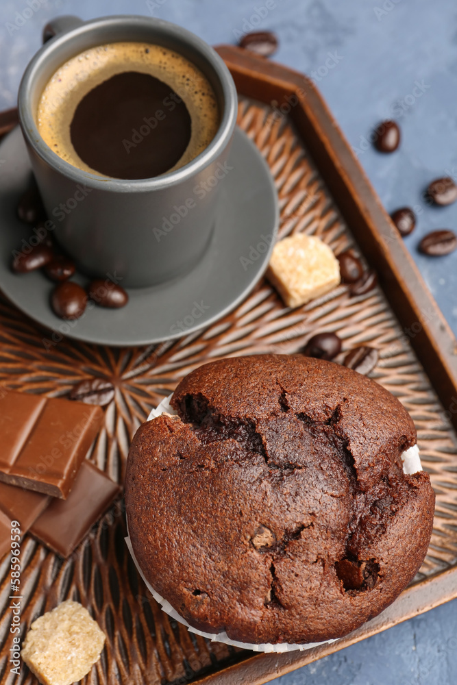 Plate with tasty chocolate cupcake and cup of coffee on blue background